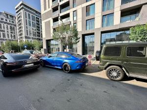zwei Autos auf einem Parkplatz vor einem Gebäude geparkt in der Unterkunft Boutique Cloud9 Pipera nearby Drpciv in Bukarest