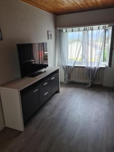 a living room with a tv and a large window at appartement 3 pce in Vicques +6 photos