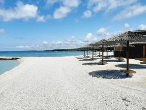 a sandy beach with umbrellas and the ocean at Villa Elizej in Fažana