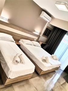 two twin beds in a room with a window at Riviera Olympus Gods in Paralia Katerinis