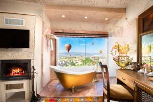 a bathroom with a tub and a fireplace with hot air balloons at Cappadocia Fairy Chimneys Selfie Cave Hotels - Balloon View Experience in Uçhisar