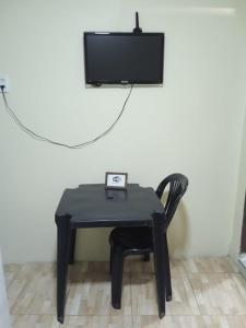 uma mesa preta com uma cadeira e uma televisão na parede em Rioli quarto 2 em Caruaru