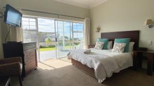 1 dormitorio con 1 cama, TV y ventana en Sir Roys at the Sea, en Port Elizabeth