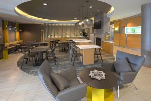 a living room with chairs and tables and a kitchen at SpringHill Suites by Marriott Albany Latham-Colonie in Albany