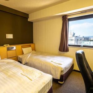 a hotel room with two beds and a window at Ramada Encore by Wyndham Amagasaki in Amagasaki