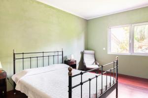 a bedroom with a bed and a chair and a window at Casa da Vigia in Santo António