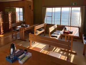 a room with benches and tables and a view of the ocean at 民宿たかはま Takahama Guest house 