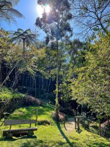 un parque con un banco de madera en el césped en Quinta da Torre 7 suítes Cachoeira SPA aquecido en Petrópolis