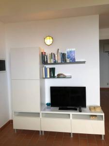 un centro de entretenimiento blanco con TV y libros en Casa Rais Dragut, en Capraia