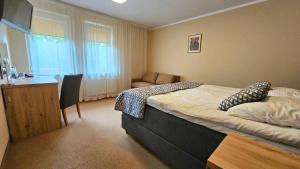 a bedroom with a bed and a desk with a chair at Hotel Sypniewo in Margonin