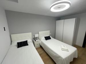 Habitación blanca con 2 camas y luz en Apartamento 1 HOME SUITES ALMERÍA, en Almería