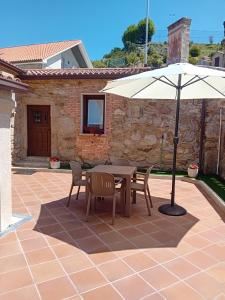 a table and chairs and an umbrella on a patio at Casa da Aldea A Fonte - Meaño in Santa Cristina