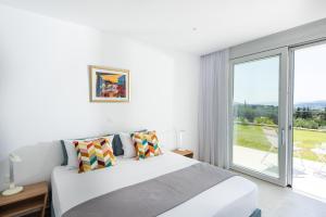 - une chambre blanche avec un lit et une grande fenêtre dans l'établissement Villa Inati, à Nípos