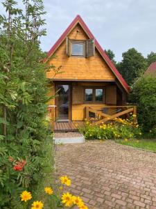 a wooden house with a patio and flowers at ŻURAWISKO - domki letniskowe Jarosławiec in Jarosławiec