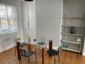 une salle à manger avec une table et des chaises en verre dans l'établissement 2BD Victorian Terrace House Ramsgate, à Ramsgate
