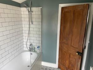 a bathroom with a bath tub with a shower and a door at 2BD Victorian Terrace House Ramsgate in Ramsgate