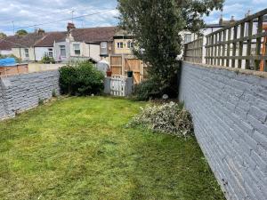 a backyard with a retaining wall and a fence at 2BD Victorian Terrace House Ramsgate in Ramsgate