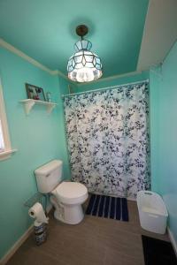 a bathroom with a toilet and a flower shower curtain at Little House by the Brook 