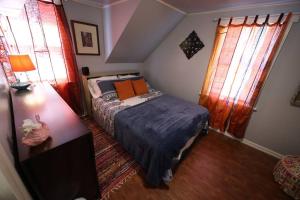 a small bedroom with a bed and two windows at Little House by the Brook 