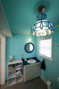 a bathroom with a sink and a mirror and a chandelier at Little House by the Brook 
