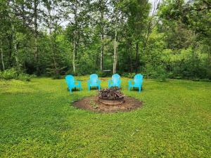 quatro cadeiras azuis sentadas à volta de uma fogueira num quintal em Little House by the Brook 