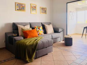 a living room with a gray couch with colorful pillows at Casa del Mayor in Playa Honda