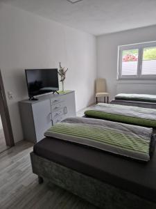 a bedroom with two beds and a television in it at Gelis Ferienwohnung in Aichstetten