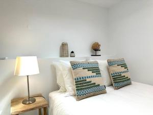ein weißes Bett mit Kissen und einer Lampe in der Unterkunft Duplex apartment 2 min from the beach in Nazaré