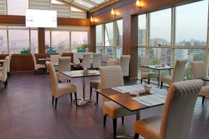 een restaurant met tafels, stoelen en ramen bij LB Suites Hotel in Bir el Djir