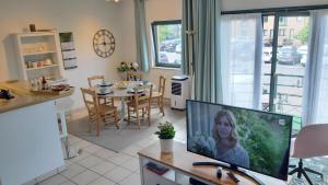 a living room with a television on a desk with a table at LLN lodge in Louvain-la-Neuve