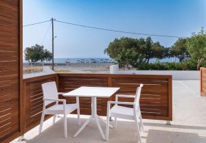een tafel en stoelen op een balkon met uitzicht op het strand bij Long Beach Resort in Ierápetra