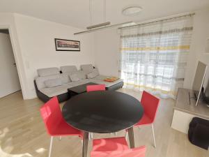 ein Wohnzimmer mit einem schwarzen Tisch und roten Stühlen in der Unterkunft Ferienwohnung Pinovas in Friedrichshafen