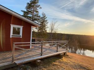 a house with a deck next to a body of water at Trevligt fritidshus med stor terrasse mot sjöen in Skillingsfors