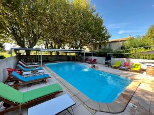 a swimming pool with chairs and avisor around it at Le Mas Saint Jacques in Le Pontet