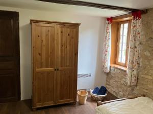 ein Schlafzimmer mit einem Holzschrank und einem Bett in der Unterkunft La Grange Du Noyer in Cornac