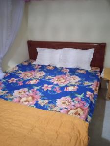 a bed with a blue comforter with pink flowers at Homestay Ngọc Thủy Điểm dừng chân lên Đồi Mâm Xôi in Mù Cang Chải