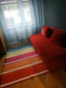 a red couch sitting in front of a window at FEIDUM quarters rooms in Trzebinia