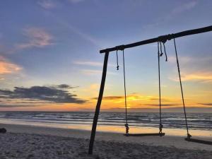 - une balançoire sur la plage avec le coucher de soleil en arrière-plan dans l'établissement Tumombuvoi Homestay (Sidi place), à Tiga Papan