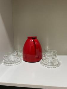 um bule de chá vermelho e três pratos de vidro numa prateleira em Flat Davisis 3 - PX da JK em Palmas