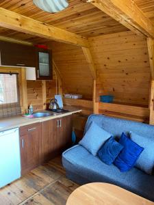 a living room with a blue couch in a cabin at ŻURAWISKO - domki letniskowe Jarosławiec in Jarosławiec