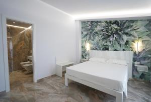 Harmony Tropea Rooms & Suites في تروبيا: غرفة نوم بسرير ابيض وجدار نباتي