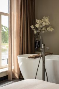 uma casa de banho com uma banheira e um vaso de flores em The Lemon Suites em Deventer