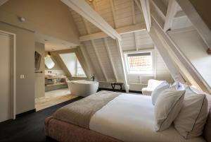 a bedroom with a bed and a bathroom with a tub at The Lemon Suites in Deventer