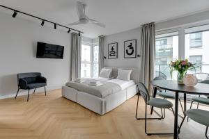 a white bedroom with a bed and a table and chairs at Blue Mandarin Marina in Gdańsk