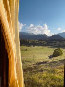 a window with a view of a field and mountains at Nadiani Hostel in Omalo