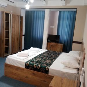 um quarto com uma cama grande e cortinas azuis em Hotel Boutique Al Hayit em Bukhara