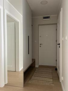 a hallway with a white door and a rug at Apartament Kasztanowa in Augustów