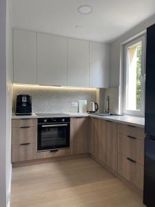 a kitchen with white cabinets and a stove and a window at Apartament Kasztanowa in Augustów