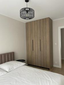 a bedroom with a bed and a wooden cabinet at Apartament Kasztanowa in Augustów