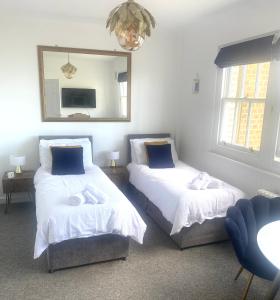 um quarto com 2 camas e um espelho em SEAFRONT SANCTUARY Beautiful Art Deco Apartment with Stunning City & Sea Views em Brighton & Hove